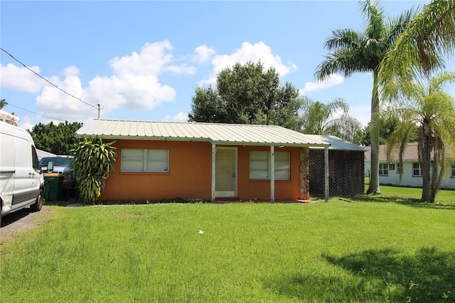 view of front of property featuring metal roof, a front lawn, and stucco siding