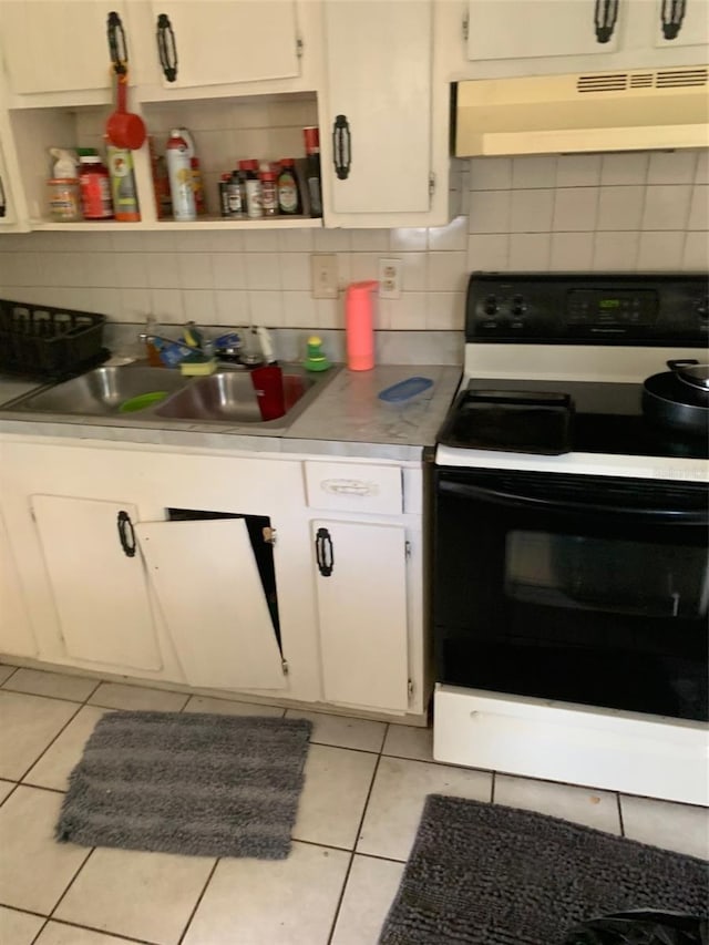 kitchen featuring electric range, light tile patterned flooring, a sink, and under cabinet range hood