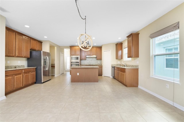 kitchen with stainless steel appliances, light tile patterned flooring, light stone countertops, and a kitchen island