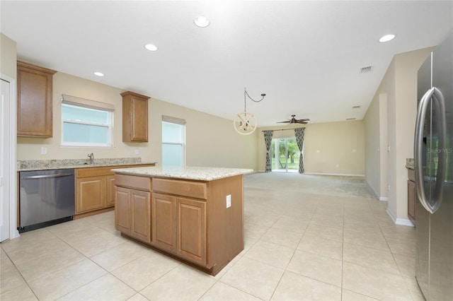 kitchen featuring appliances with stainless steel finishes, light stone counters, a kitchen island, ceiling fan, and light tile patterned flooring