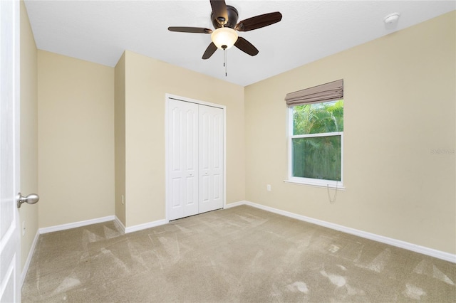 unfurnished bedroom with ceiling fan, a closet, and light colored carpet