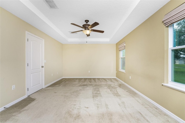 carpeted spare room with ceiling fan and a tray ceiling