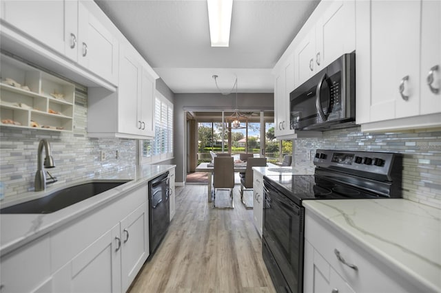 kitchen with white cabinetry, sink, light stone counters, and black appliances