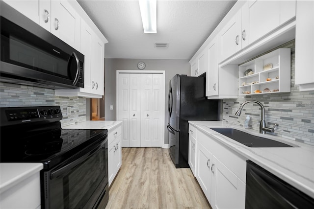 kitchen featuring sink, black appliances, white cabinets, and light stone countertops