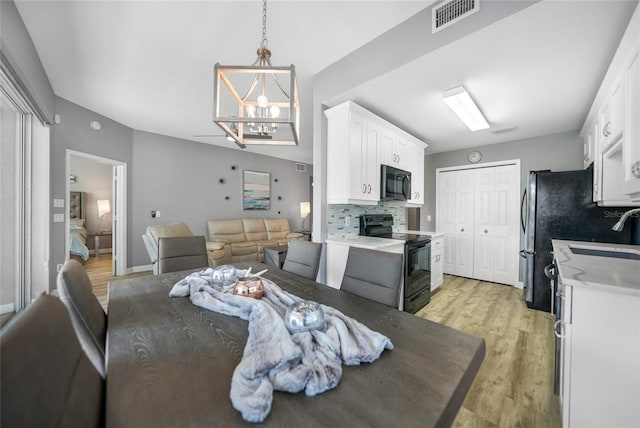 dining area with sink, an inviting chandelier, and light wood-type flooring