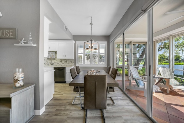 dining space with sink, light hardwood / wood-style flooring, and a notable chandelier