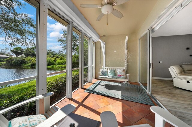 sunroom / solarium featuring a water view and ceiling fan