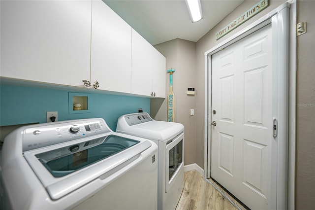 clothes washing area featuring cabinets, separate washer and dryer, and light hardwood / wood-style floors