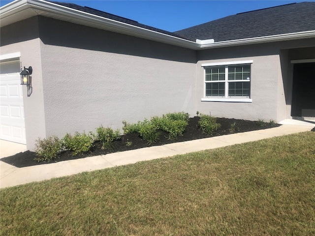 view of side of property featuring a garage and a lawn