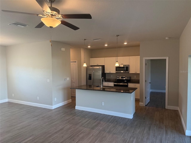 kitchen with hanging light fixtures, dark hardwood / wood-style flooring, an island with sink, white cabinets, and appliances with stainless steel finishes