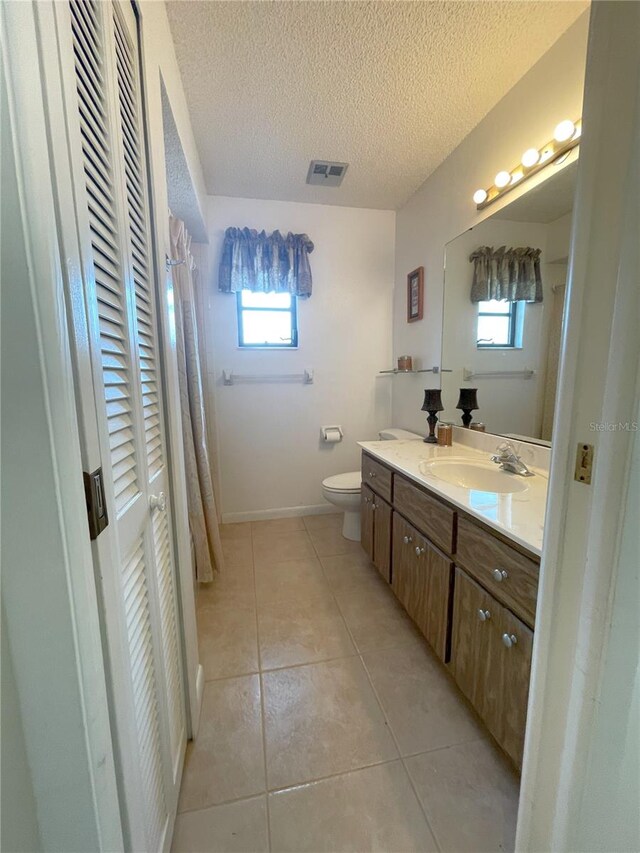 bathroom featuring tile patterned floors, vanity, toilet, and a textured ceiling