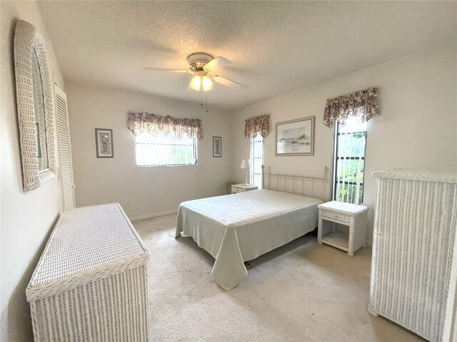 carpeted bedroom with multiple windows, ceiling fan, and a textured ceiling