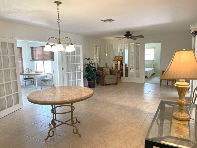 tiled dining area with french doors and ceiling fan with notable chandelier