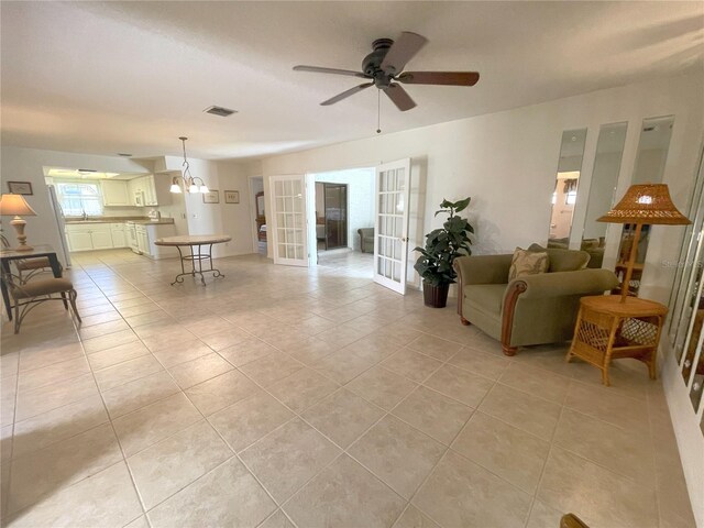 tiled living room featuring french doors and ceiling fan with notable chandelier