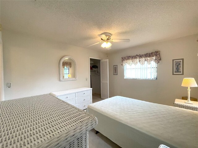 bedroom with a textured ceiling, a spacious closet, a closet, and ceiling fan