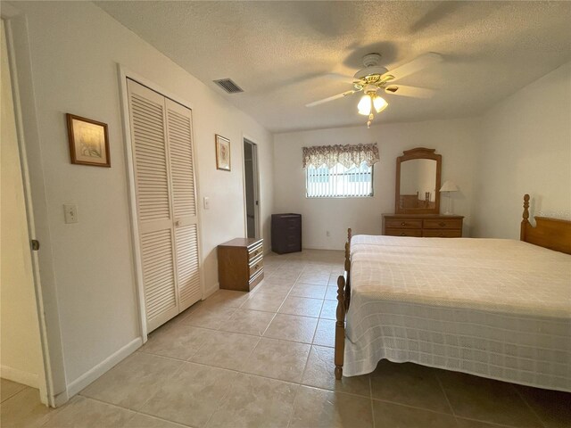 tiled bedroom featuring ceiling fan, a textured ceiling, and a closet