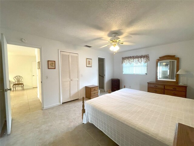 bedroom featuring ceiling fan, light tile patterned floors, and a textured ceiling