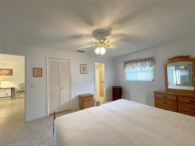 bedroom featuring light tile patterned floors, a textured ceiling, a closet, and ceiling fan