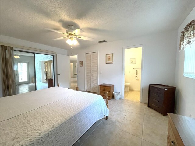 bedroom with ceiling fan, light tile patterned floors, a textured ceiling, and ensuite bath