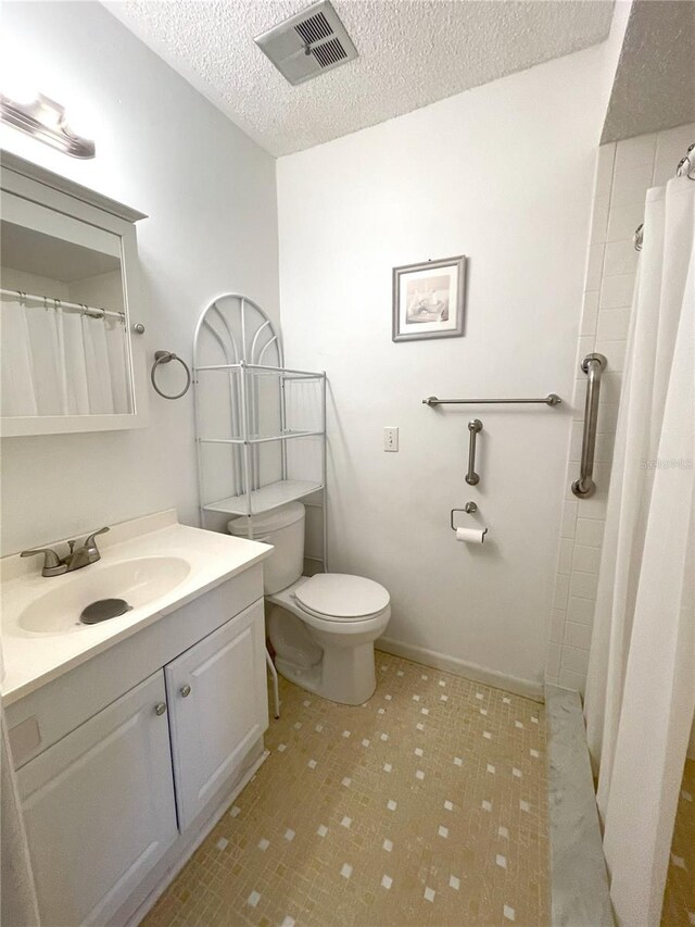 bathroom with vanity, toilet, a textured ceiling, and walk in shower