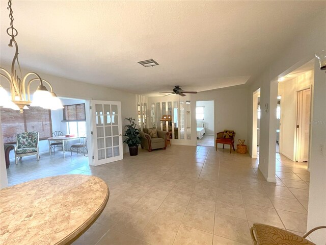 interior space featuring light tile patterned floors, ceiling fan with notable chandelier, and plenty of natural light