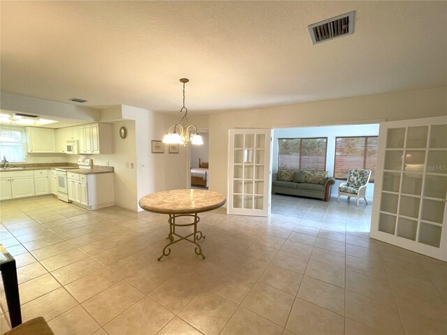 unfurnished dining area with sink, light tile patterned flooring, and a chandelier