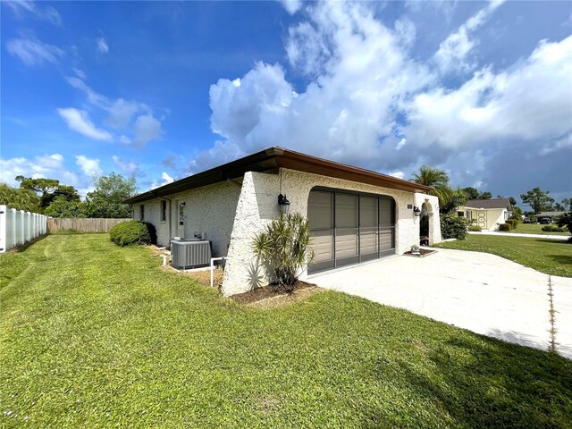 view of property exterior with central AC unit, a garage, and a yard