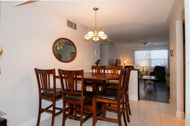 tiled dining room with crown molding, ceiling fan with notable chandelier, and a textured ceiling