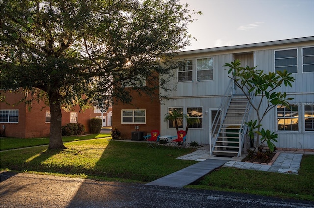 view of front facade with a front yard and central air condition unit