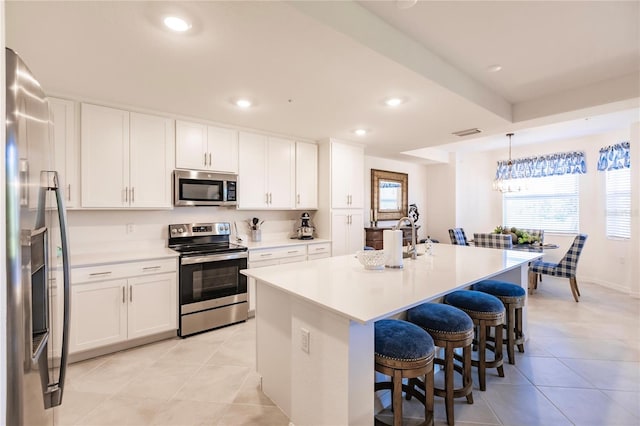 kitchen featuring appliances with stainless steel finishes, pendant lighting, white cabinetry, and light tile patterned floors