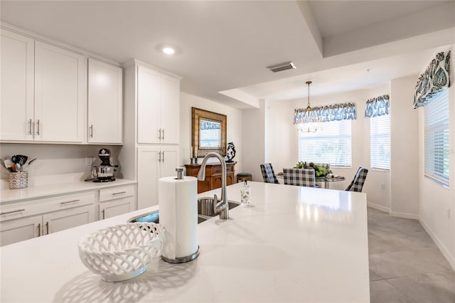 kitchen with white cabinets, a notable chandelier, plenty of natural light, and light tile patterned floors