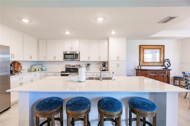 kitchen featuring a breakfast bar, a center island with sink, appliances with stainless steel finishes, and light tile patterned flooring