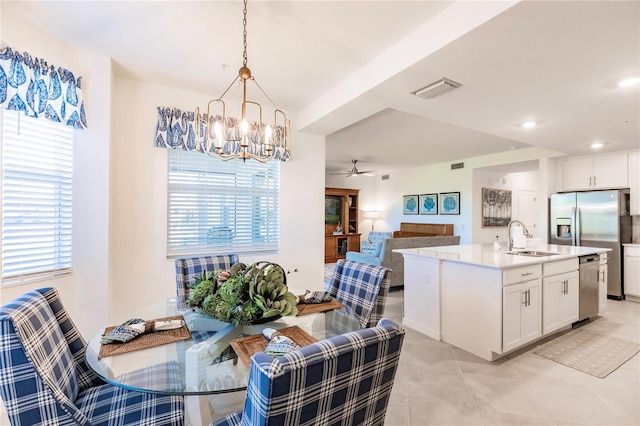 tiled dining space featuring ceiling fan with notable chandelier, sink, and a healthy amount of sunlight