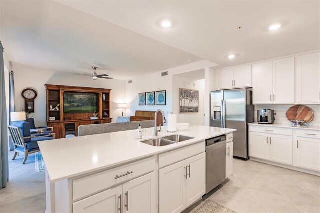 kitchen with light tile patterned floors, sink, stainless steel appliances, and a center island with sink