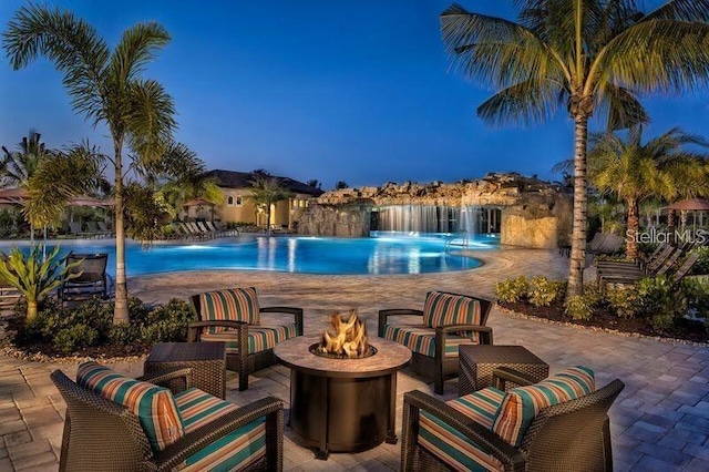 view of swimming pool with pool water feature, a patio, and a fire pit