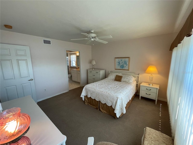 bedroom with ceiling fan, connected bathroom, and dark carpet