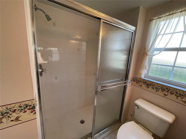 bathroom with a healthy amount of sunlight, an enclosed shower, and toilet