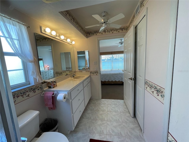 bathroom featuring toilet, vanity, tile patterned flooring, a tray ceiling, and ceiling fan