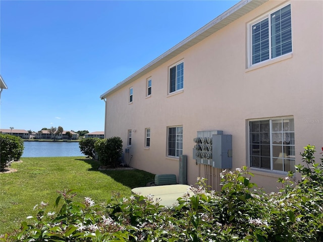 view of side of home featuring a water view and a lawn