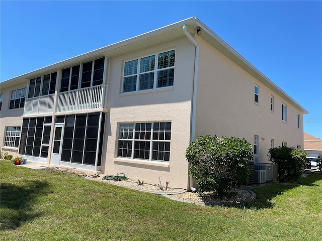 rear view of house with central AC and a yard