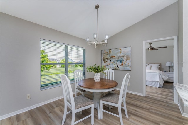 dining area featuring ceiling fan with notable chandelier, vaulted ceiling, and light hardwood / wood-style floors