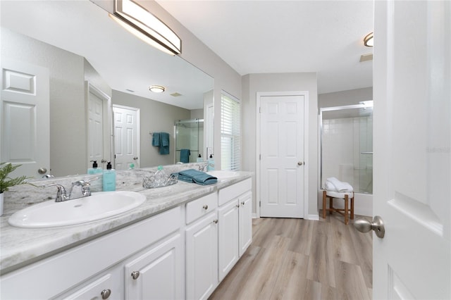 bathroom featuring double sink vanity, walk in shower, and wood-type flooring