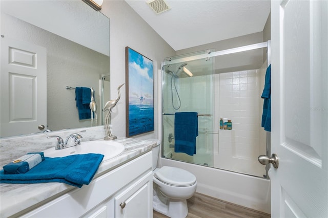 full bathroom featuring toilet, bath / shower combo with glass door, vanity, hardwood / wood-style floors, and a textured ceiling