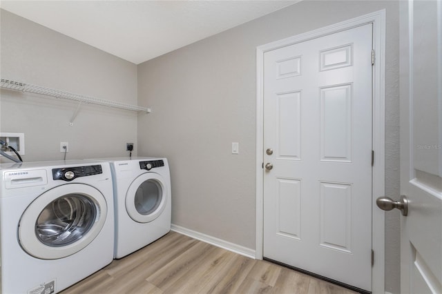 clothes washing area with light hardwood / wood-style flooring and washer and clothes dryer