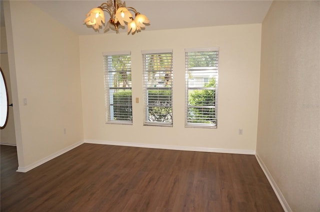 empty room with dark wood-type flooring and a chandelier