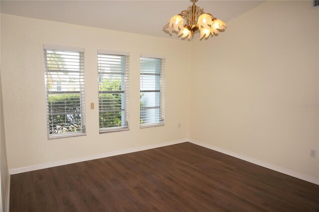 empty room featuring dark hardwood / wood-style flooring and an inviting chandelier