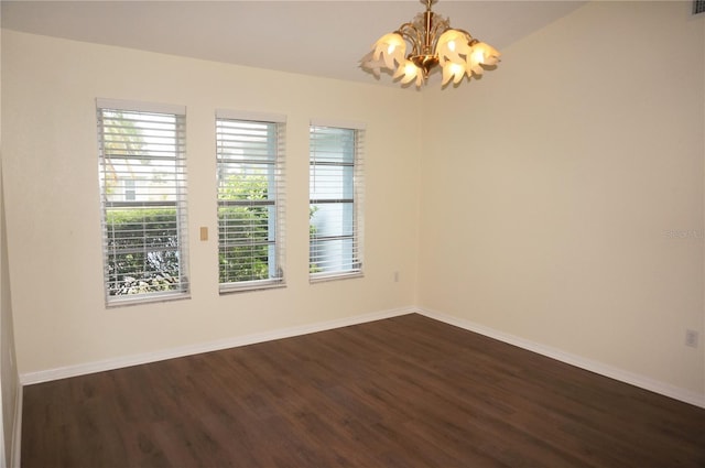 spare room with an inviting chandelier and dark hardwood / wood-style flooring