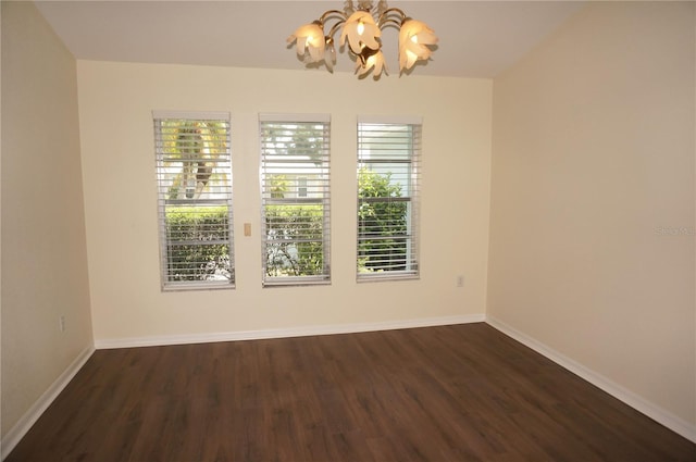 unfurnished room featuring dark wood-type flooring and an inviting chandelier