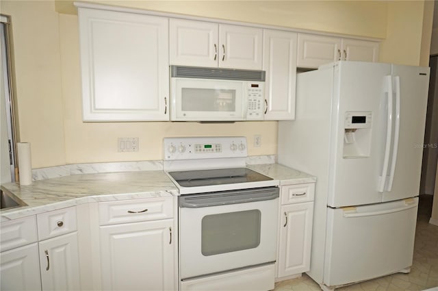 kitchen featuring white appliances, light tile patterned flooring, and white cabinets