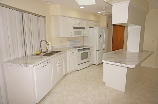 kitchen with sink, white appliances, ceiling fan, a skylight, and white cabinets